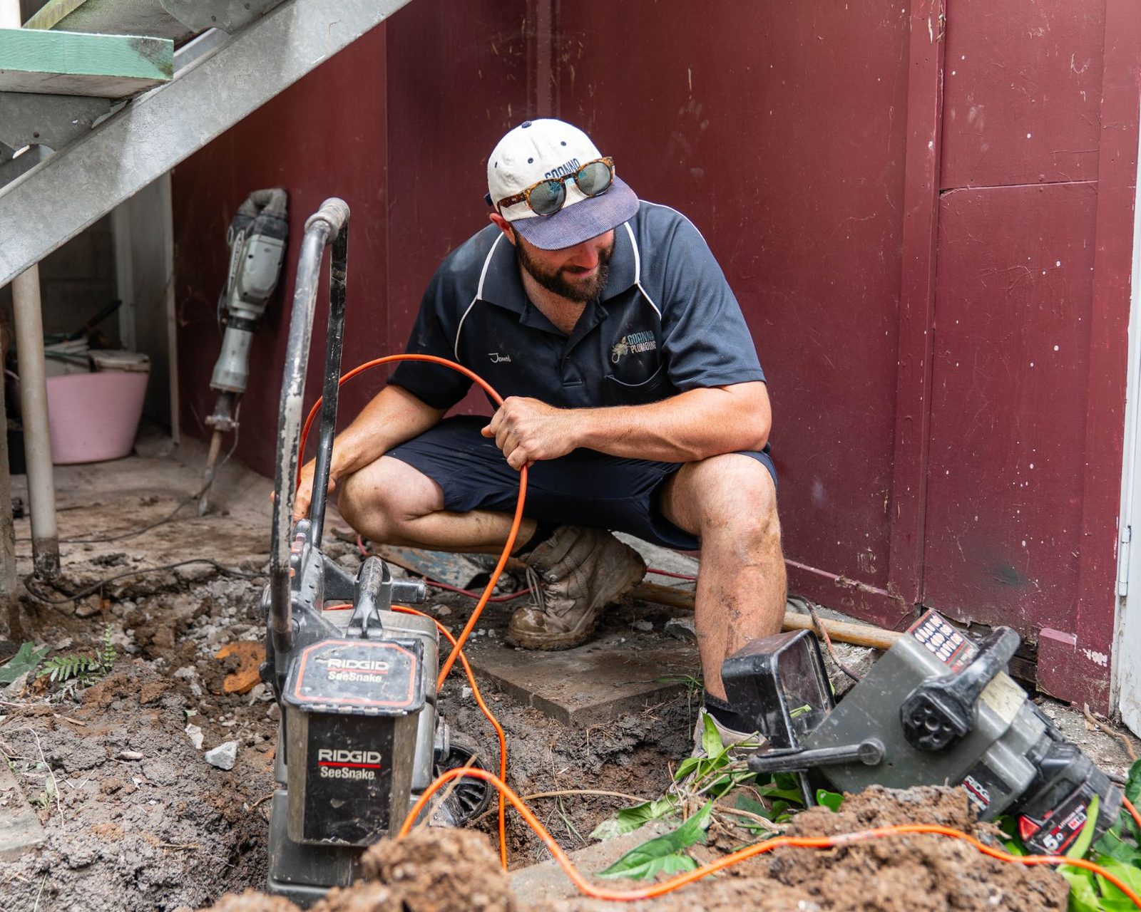 Jarred feeding a Ridgid SeeSnake drain camera into a sewer line under a Queenslander