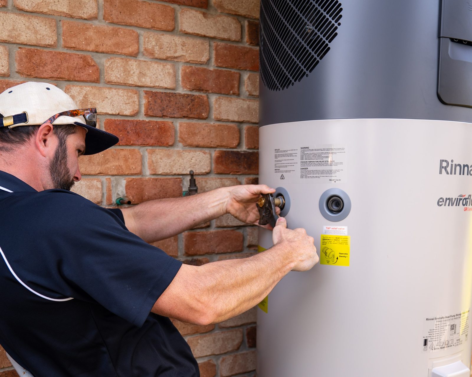 Jarred from Goanna Plumbing checking the compliance tags and valves on a hot water system