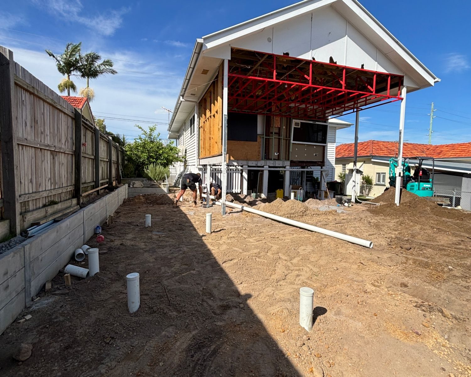 New drainage stubs set out across the site of a Brisbane home extension, with the raised house behind
